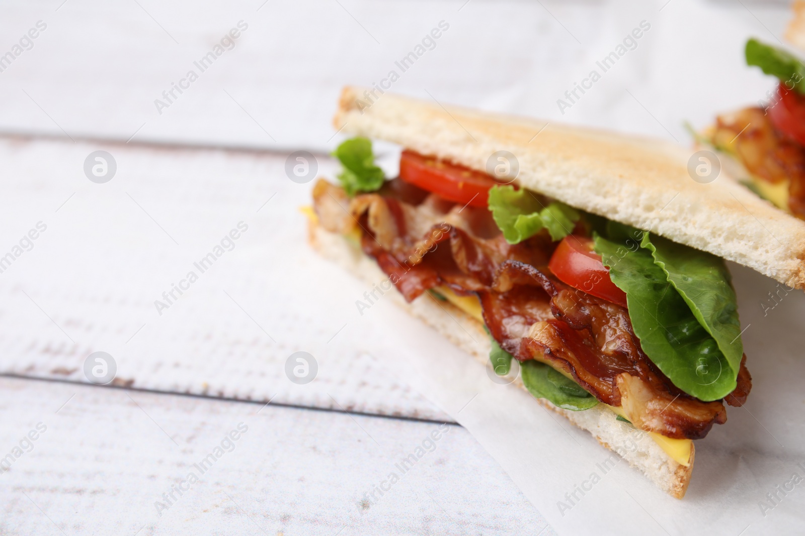 Photo of Delicious sandwiches with fried bacon on wooden rustic table, closeup. Space for text