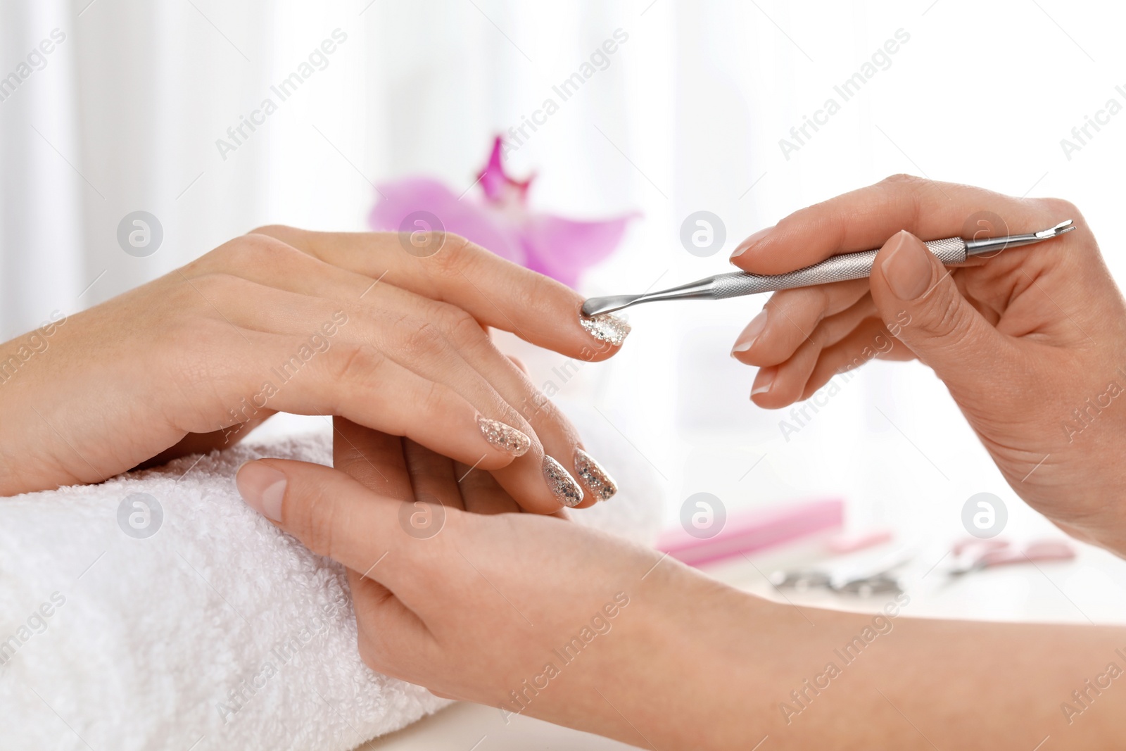 Photo of Manicurist preparing client's fingernail cuticles in salon, closeup