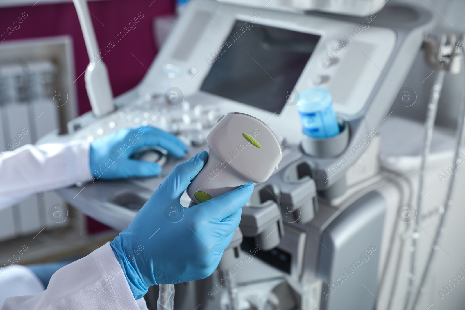 Photo of Sonographer holding ultrasound machine probe in clinic, closeup