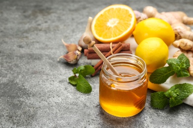 Photo of Honey and other fresh products on grey table, space for text. Natural antibiotics