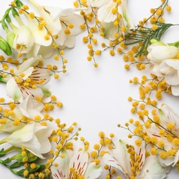 Photo of Frame of mimosa, alstroemeria and freesia flowers on white background, flat lay. Space for text