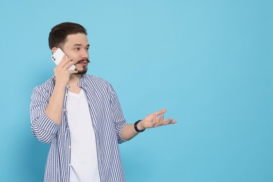 Man talking on smartphone against light blue background. Space for text