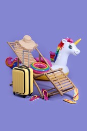 Deck chair, suitcase and beach accessories on purple background. Summer vacation