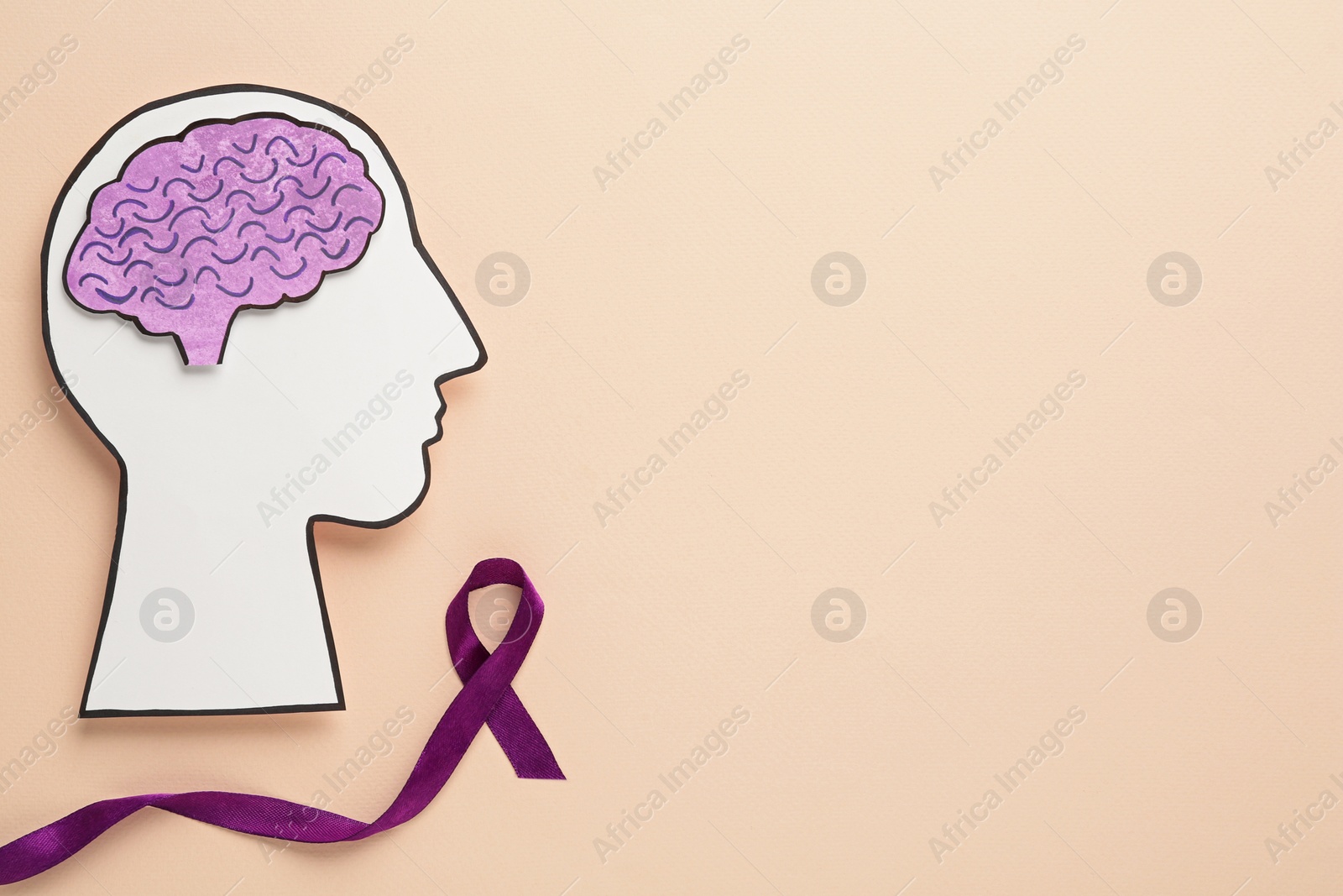 Photo of Human head cutout with brain near purple ribbon on beige background, flat lay. Epilepsy awareness