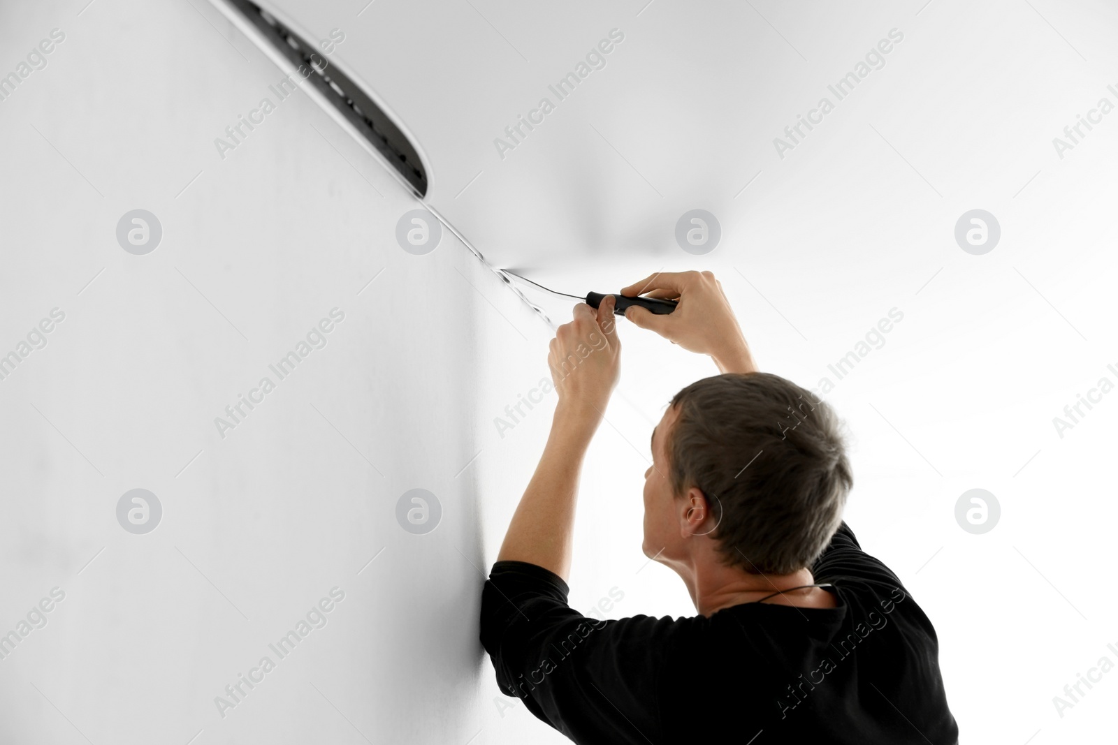 Photo of Repairman installing white stretch ceiling in room