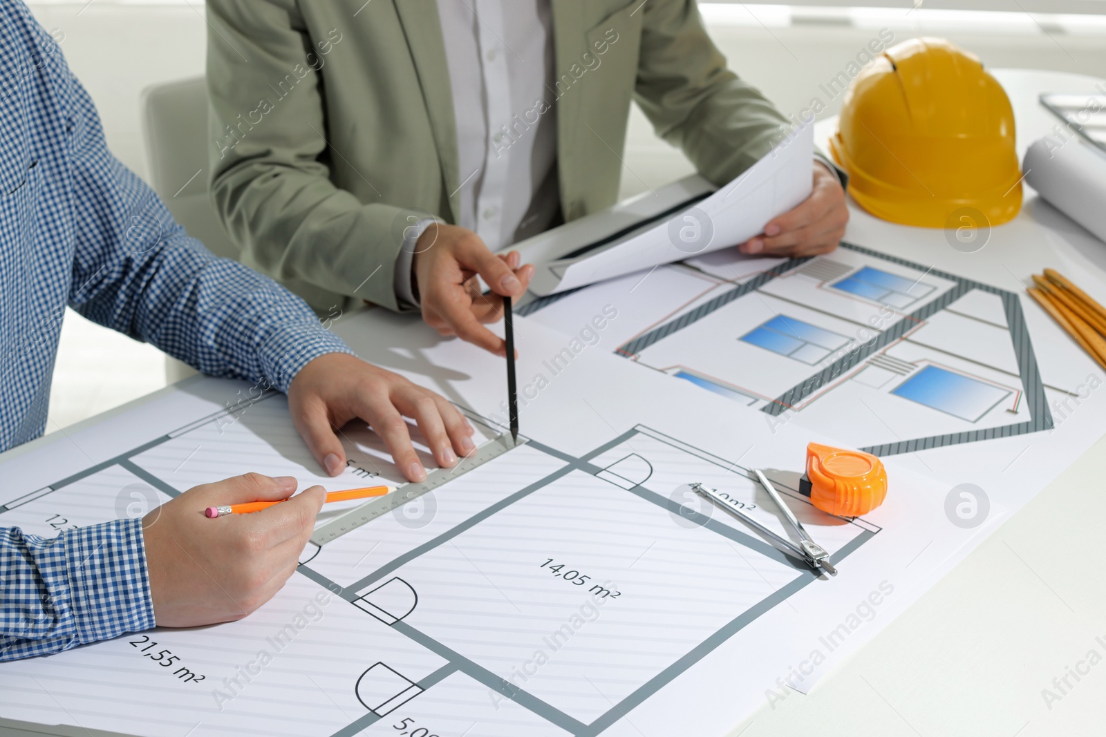 Photo of Architects working with construction drawings at table in office, closeup