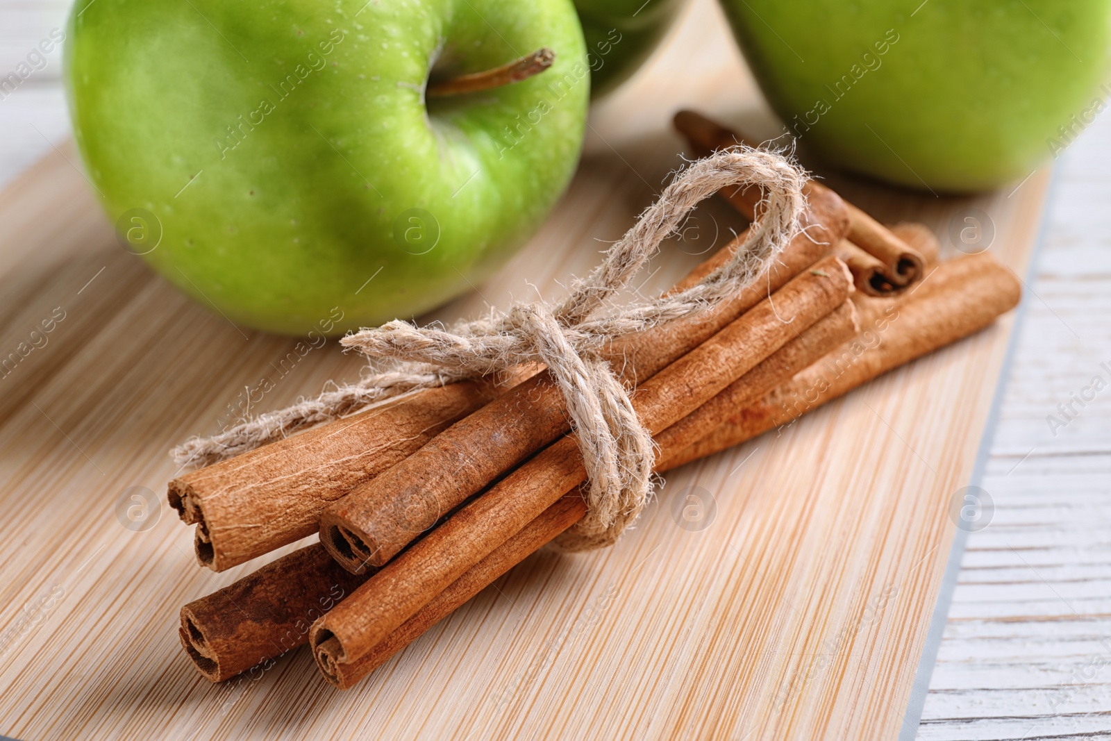 Photo of Fresh apple and cinnamon sticks on wooden board