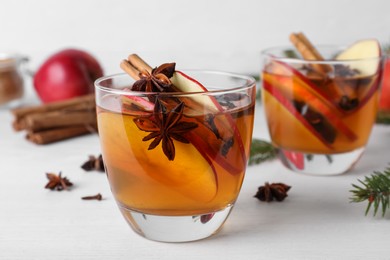 Photo of Hot mulled cider, ingredients and fir branches on white wooden table