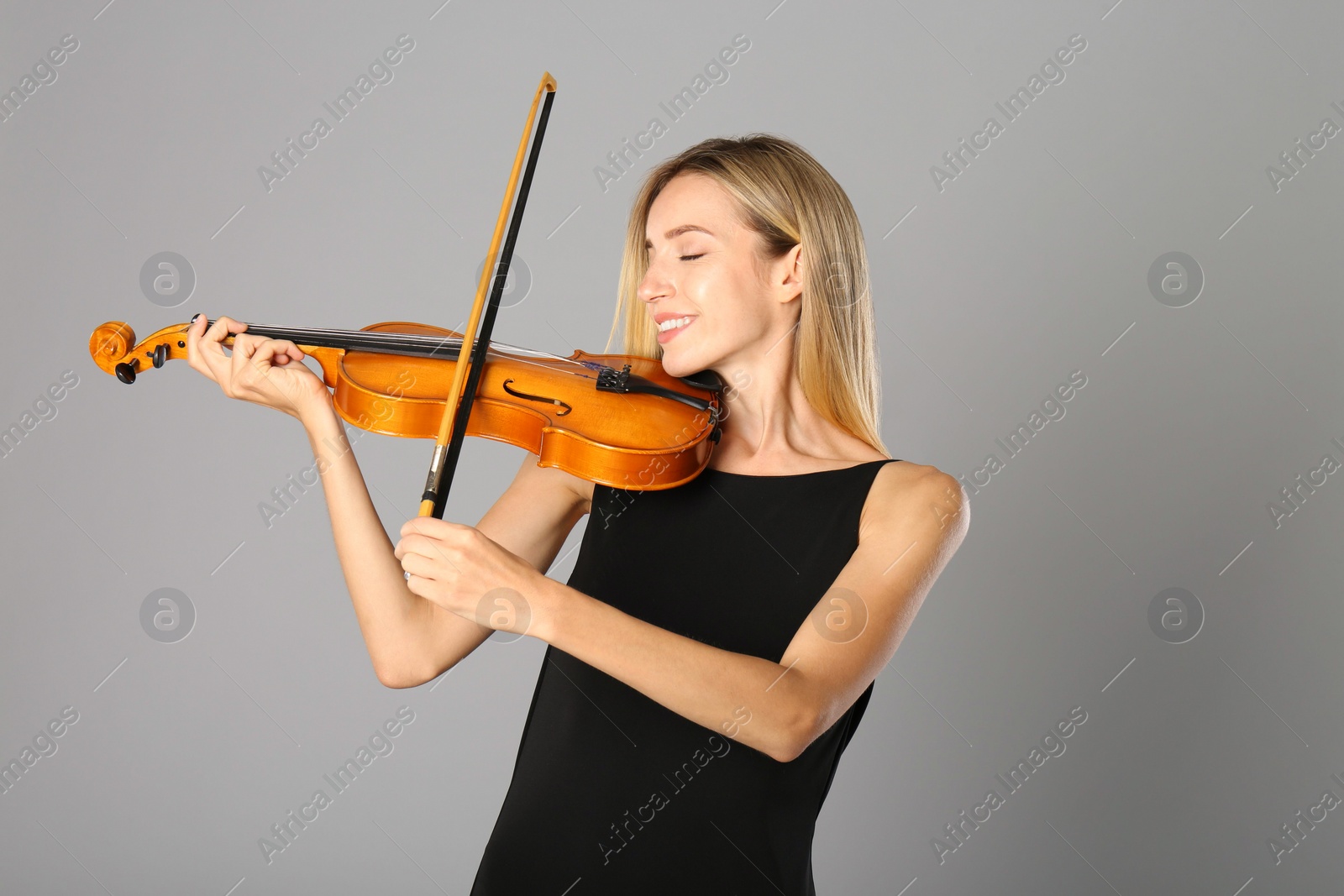 Photo of Beautiful woman playing violin on grey background