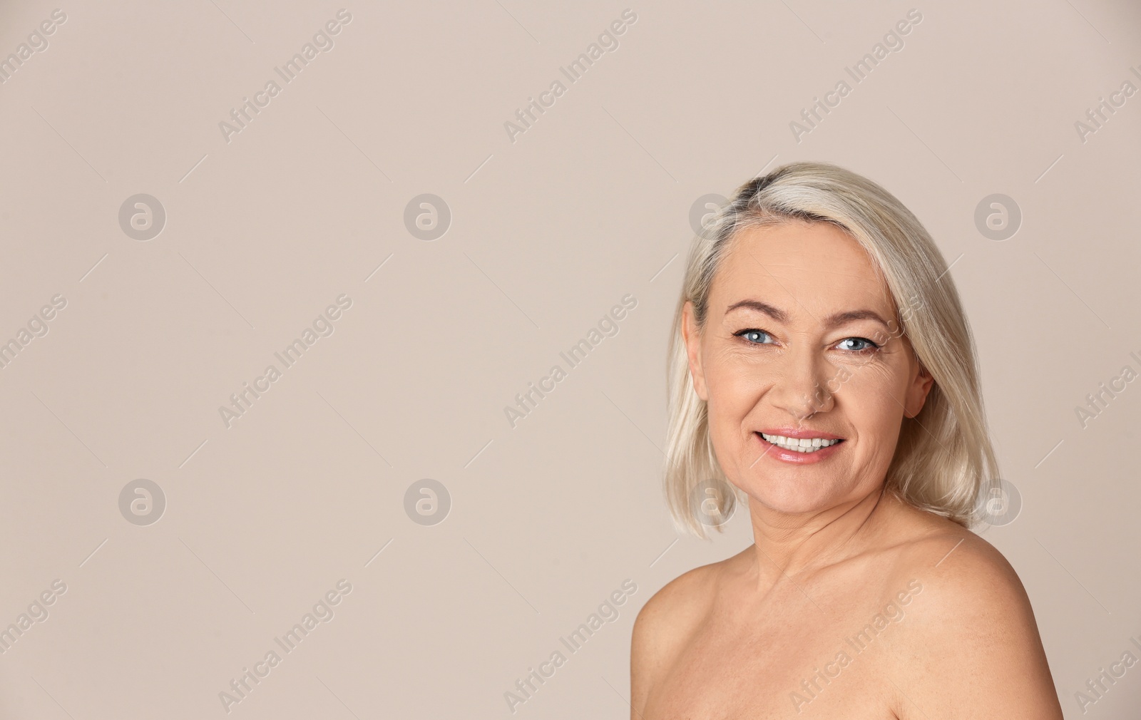 Photo of Portrait of beautiful mature woman on beige background. Space for text