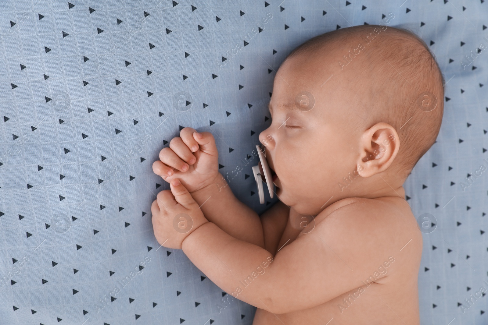 Photo of Cute little baby with pacifier sleeping on bed, top view