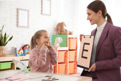 Speech therapist working with little girl in office