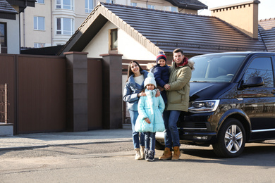 Photo of Happy family with little children near modern car on street