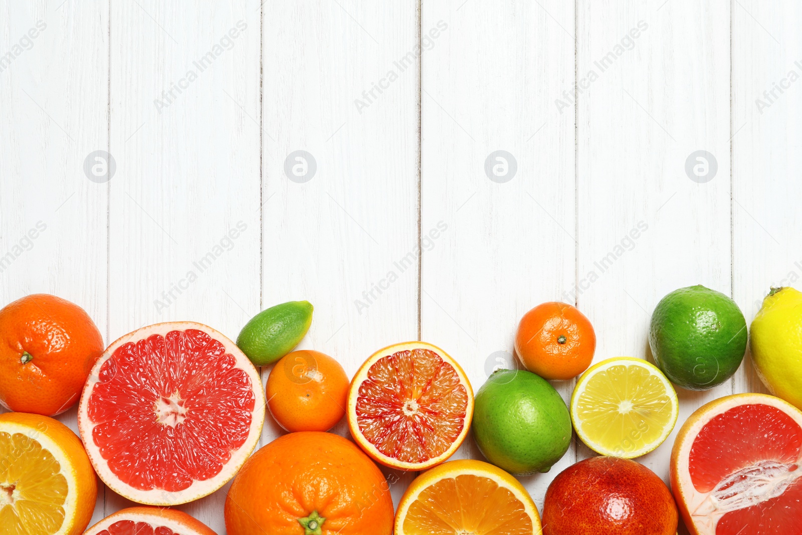 Photo of Flat lay composition with different citrus fruits and space for text on white wooden background