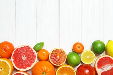 Flat lay composition with different citrus fruits and space for text on white wooden background