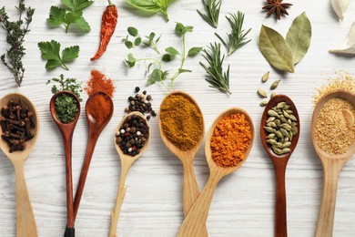 Photo of Spoons with different spices and herbs on white wooden table, flat lay