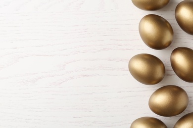 Photo of Many golden eggs and space for text on wooden background, top view