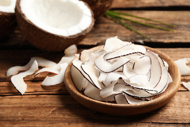 Photo of Delicious coconut chips in plate on wooden table