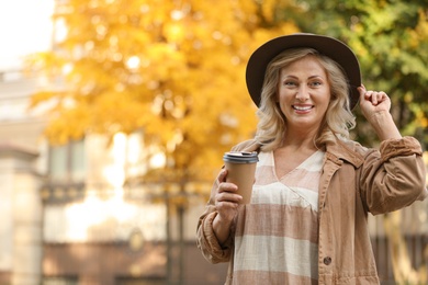 Photo of Beautiful mature woman with cup of coffee outdoors