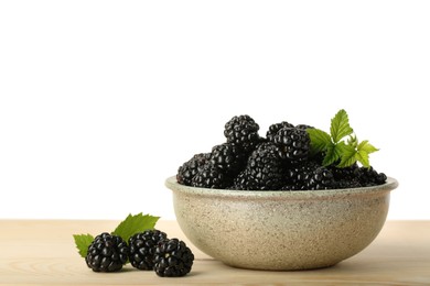 Photo of Bowl and fresh ripe blackberries on wooden table against white background, space for text