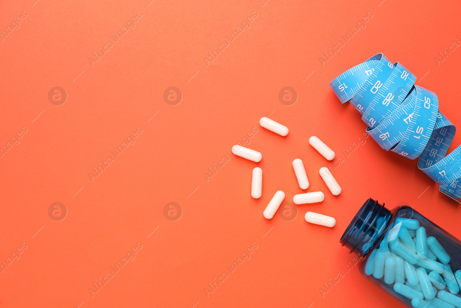 Photo of Jar of weight loss pills and measuring tape on coral background, flat lay. Space for text