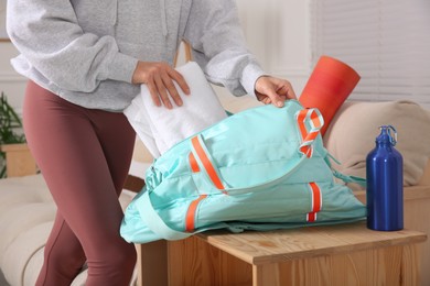 Woman packing sports stuff for training into bag at home, closeup