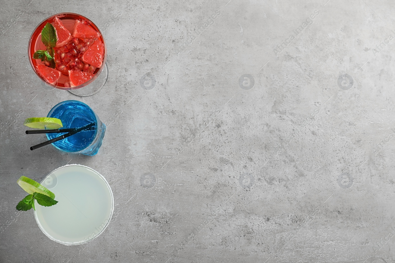 Photo of Glasses of tasty refreshing cocktails on grey background, flat lay. Space for text