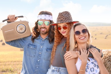 Photo of Happy hippie friends with radio receiver in field