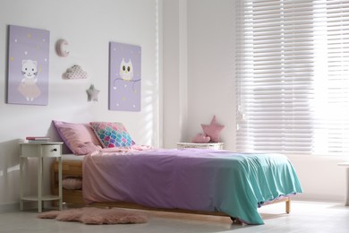 Photo of Bed with colorful linen in stylish children's room. Interior design