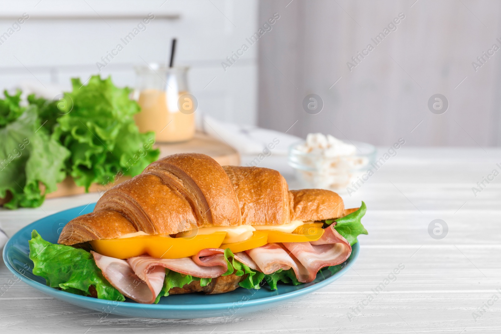 Photo of Tasty croissant sandwich with ham on white wooden table
