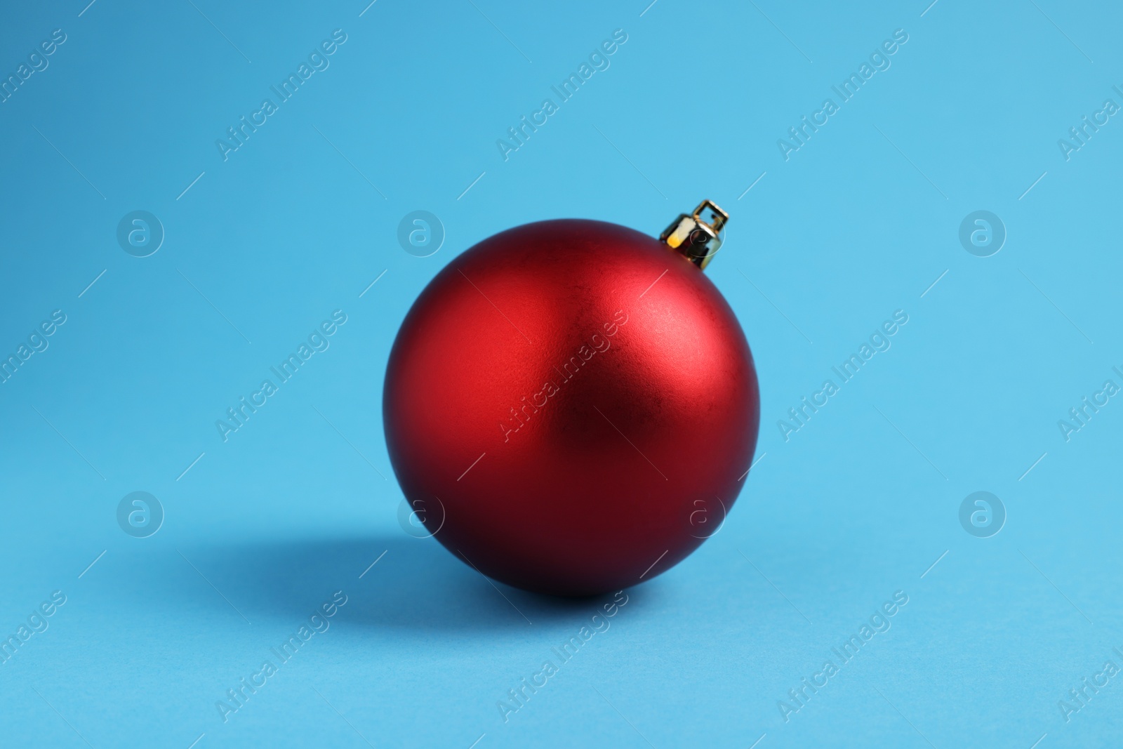 Photo of One red Christmas ball on light blue background