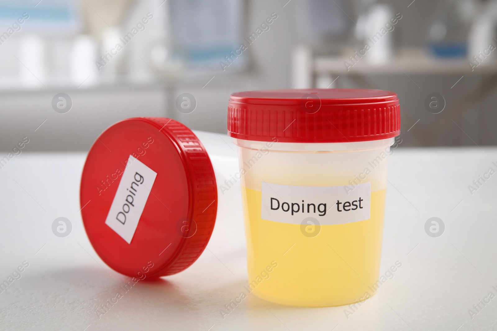 Photo of Jar with urine sample and empty one on white table. Doping control