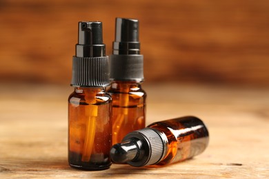 Photo of Bottles with oil on wooden table, closeup. Natural cosmetics