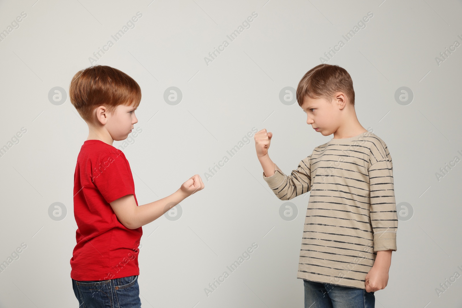 Photo of Boys with clenched fists on light grey background. Children's bullying