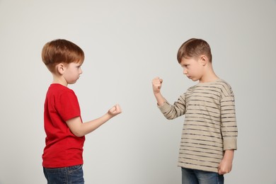 Photo of Boys with clenched fists on light grey background. Children's bullying