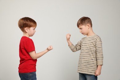 Boys with clenched fists on light grey background. Children's bullying