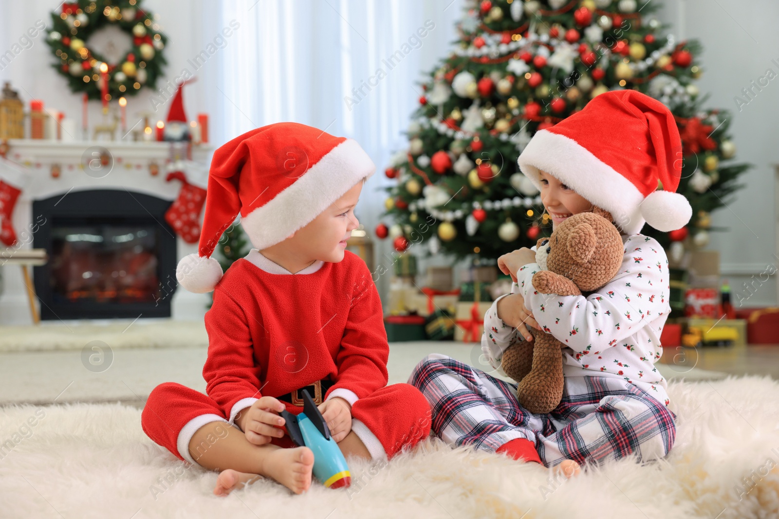 Photo of Cute little children with toys in room decorated for Christmas