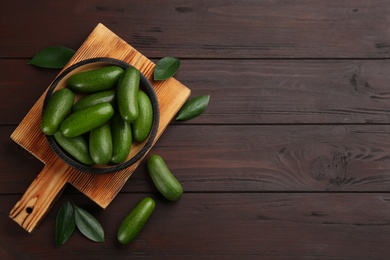 Fresh avocados with green leaves on wooden table, flat lay. Space for text