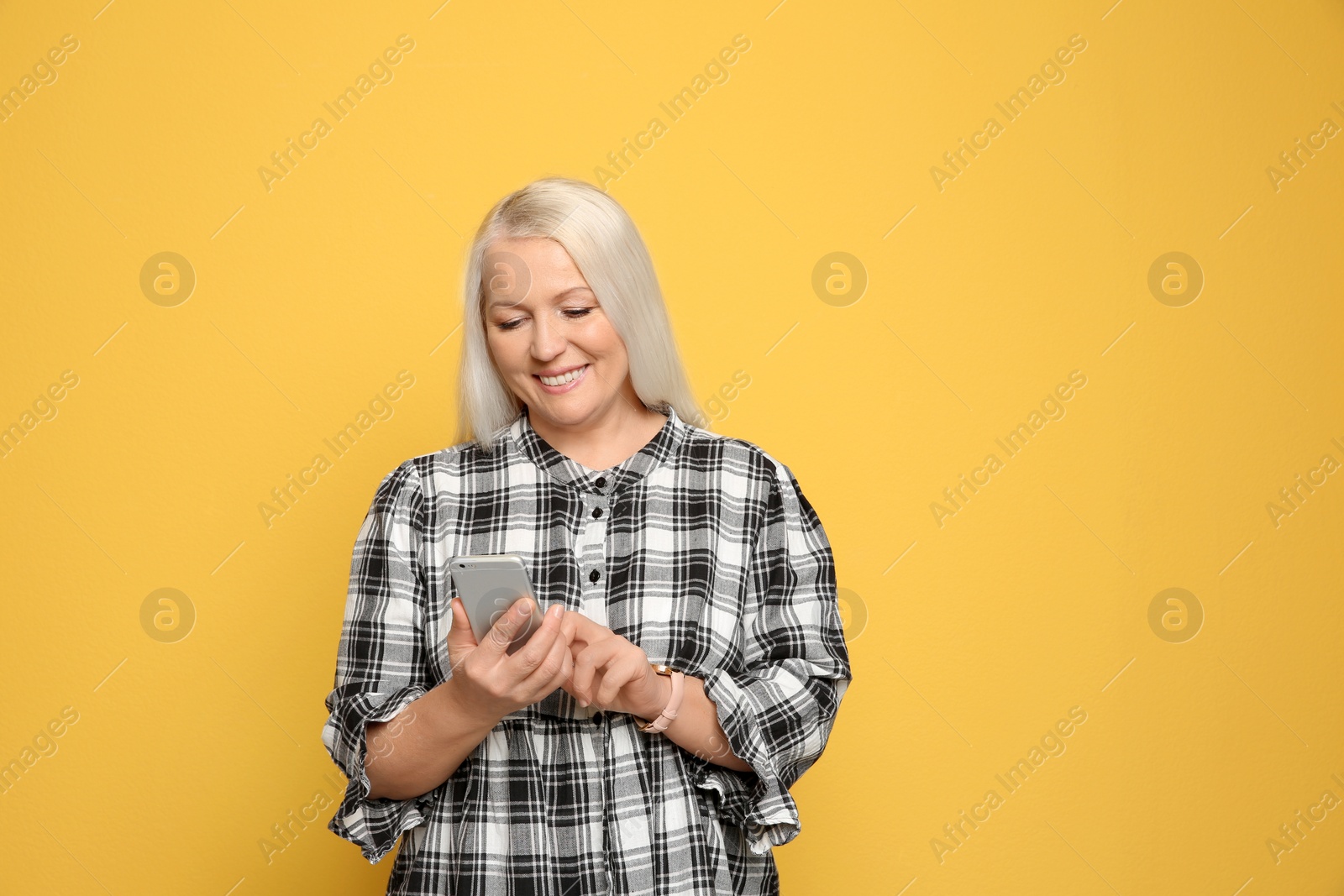 Photo of Mature woman using mobile phone on color background