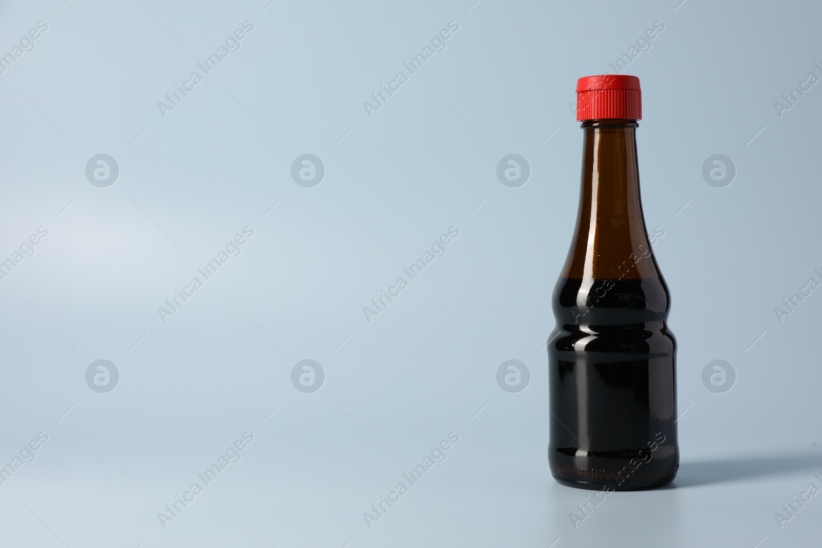 Photo of Bottle with soy sauce on light grey background, space for text