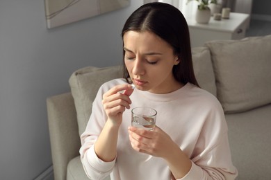Photo of Young woman taking abortion pill at home