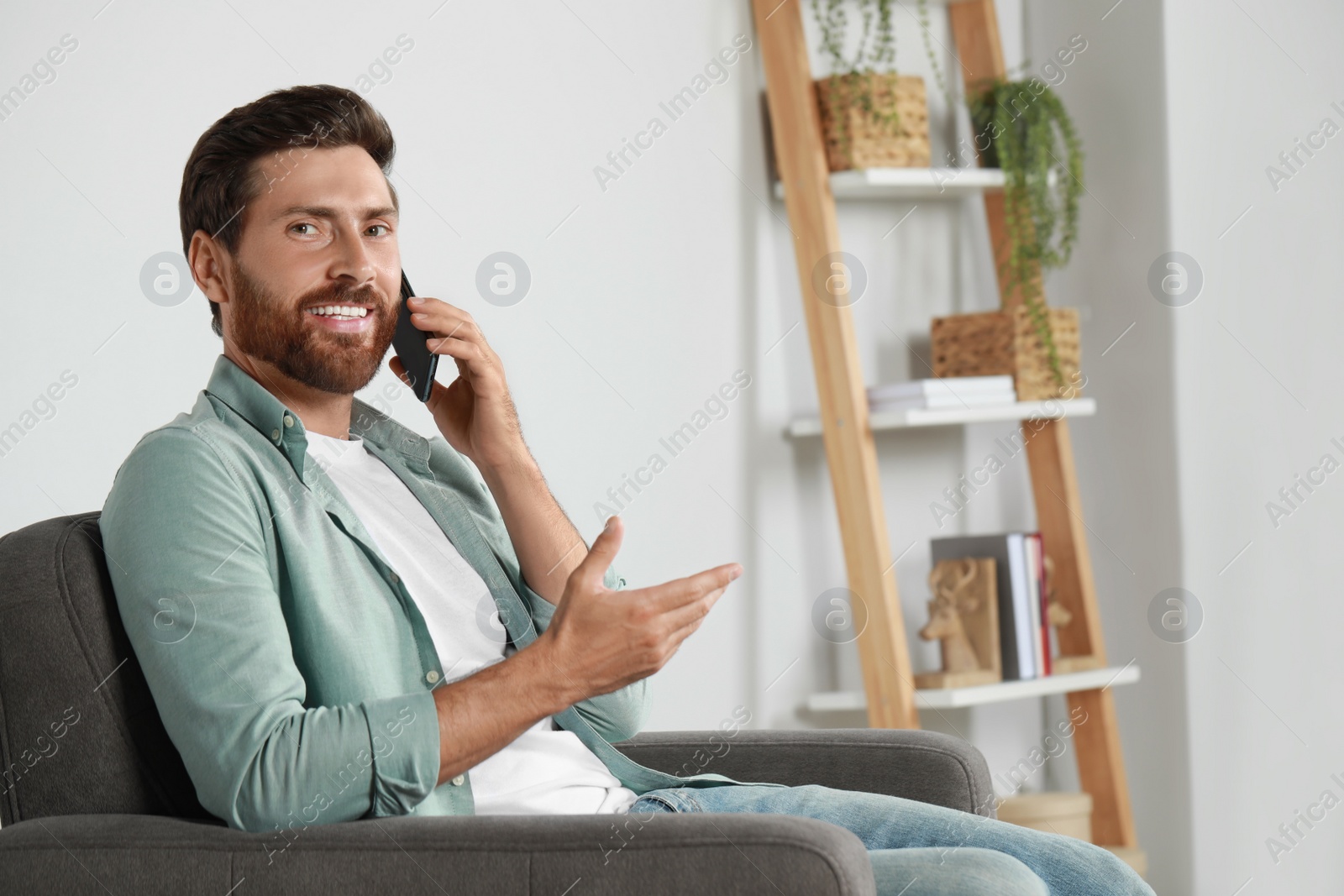 Photo of Handsome man talking on phone at home, space for text