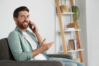 Photo of Handsome man talking on phone at home, space for text