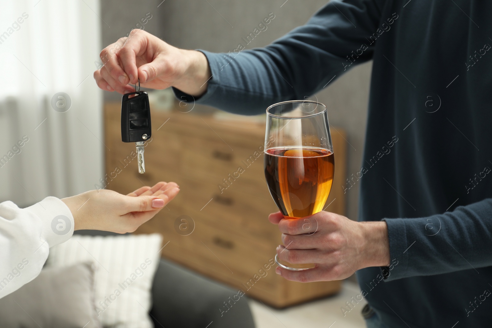 Photo of Man with glass of alcoholic drink giving car key to woman, closeup. Don't drink and drive concept