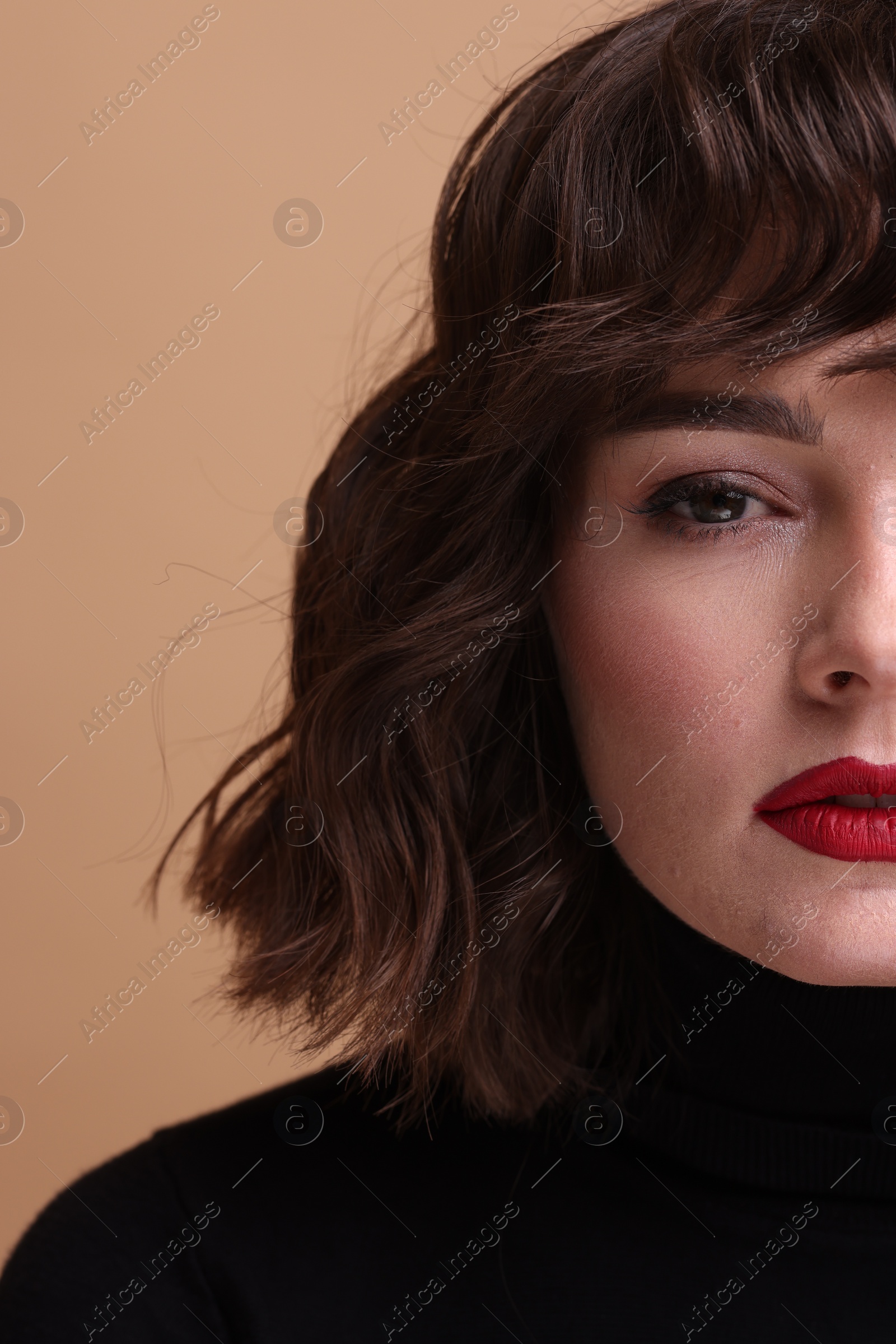 Photo of Beautiful young woman with wavy hairstyle on beige background, closeup