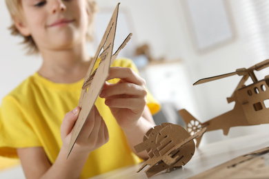 Little boy making carton toys at table indoors, closeup. Creative hobby