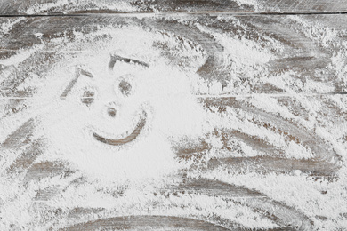 Photo of Smiling face made with flour on wooden table, top view. Space for text