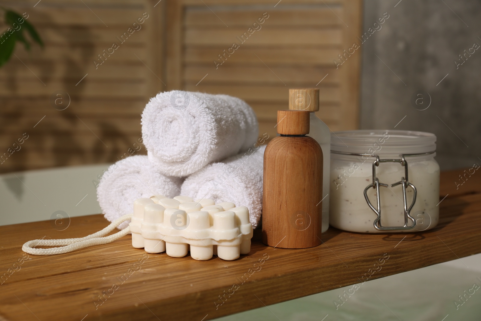 Photo of Wooden tray with spa products and towels on bath tub in bathroom