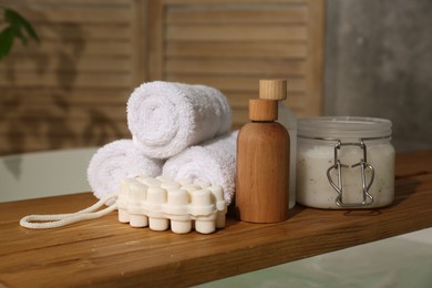 Photo of Wooden tray with spa products and towels on bath tub in bathroom