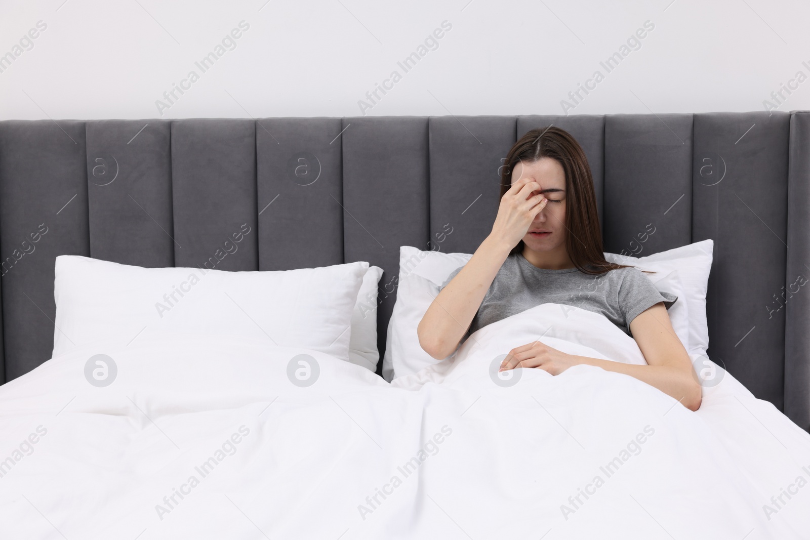 Photo of Sad woman suffering from headache in bed indoors, space for text